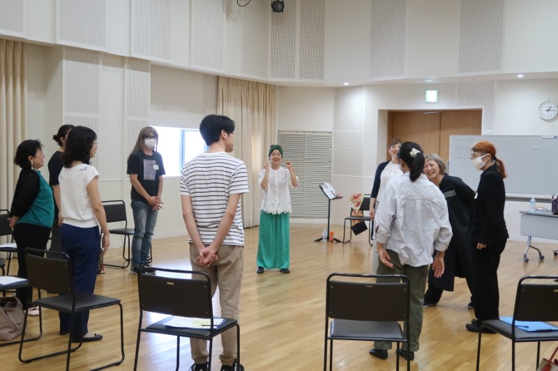 練習室で、参加者たちが円になって立っている様子。